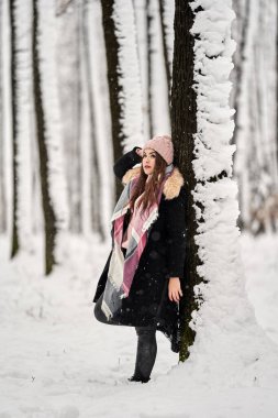 Genç beyaz kadın ormanda karda oynarken eğleniyor.