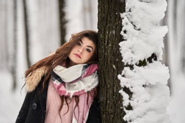 Genç beyaz kadın ormanda karda oynarken eğleniyor.