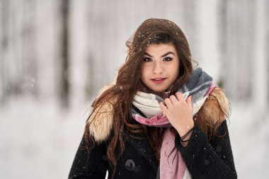 Genç beyaz kadın ormanda karda oynarken eğleniyor.