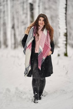 Genç beyaz kadın ormanda karda oynarken eğleniyor.