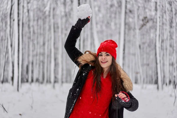 冬の雪深い森の中に赤いキャップを持つ若い白人女性の肖像画 — ストック写真