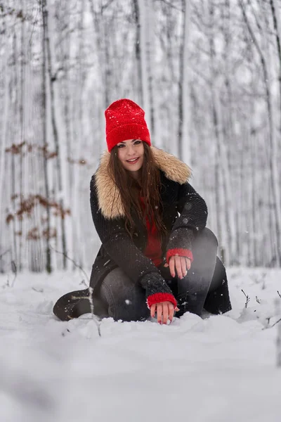 冬季雪地森林里头戴红帽的年轻高加索女人的画像 — 图库照片