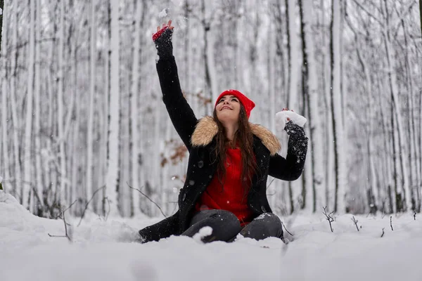 冬の雪深い森の中に赤いキャップを持つ若い白人女性の肖像画 — ストック写真