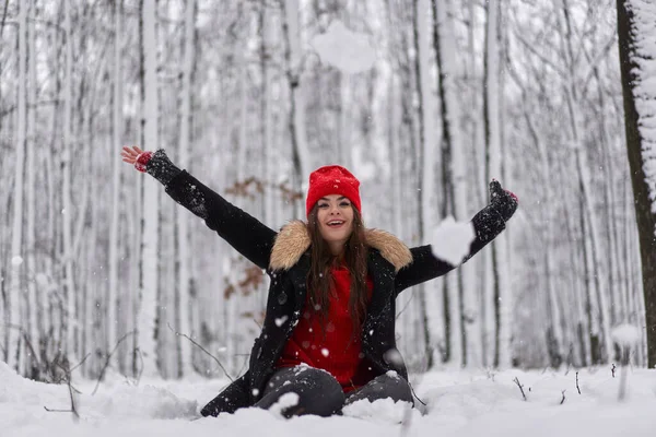 冬の雪深い森の中に赤いキャップを持つ若い白人女性の肖像画 — ストック写真