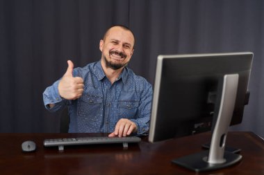 İşadamı masasında bilgisayar ve belgelerle çalışıyor.