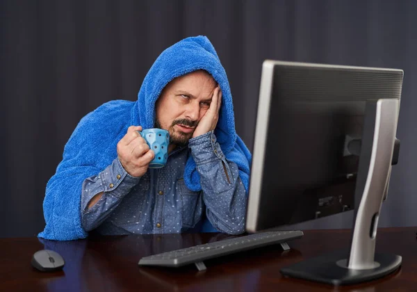 Covid 19のビジネスマンは厚いタオルで覆われている彼のコンピュータ上で作業しながら熱いお茶を飲む — ストック写真
