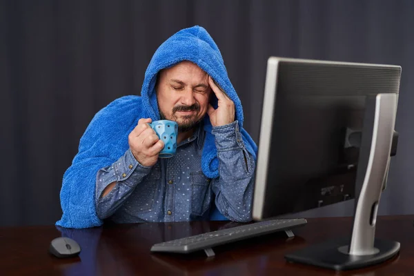 与Covid 19一起工作的商人在他的电脑上工作时 被厚厚的毛巾覆盖着 一边喝着热茶 — 图库照片
