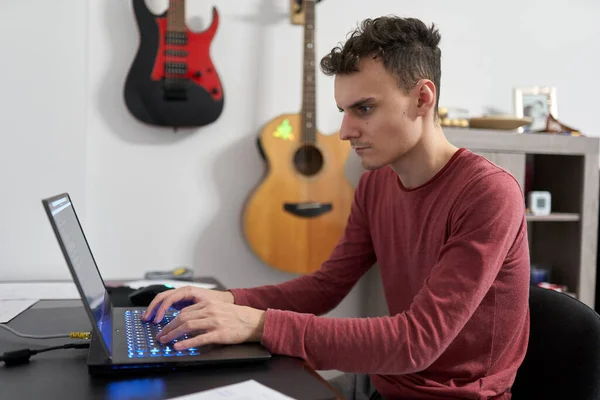 Young IT student writing code on his laptop for the University, online courses