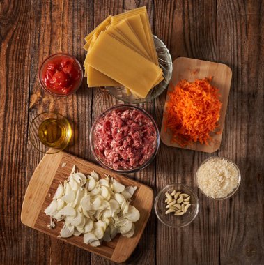 Tahta üzerinde lazanya tarifi malzemelerinin olduğu düz bir kare.