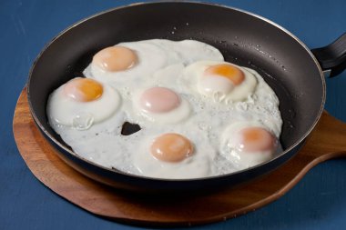 Kızartma tavasında beş yumurta, pişiyor.