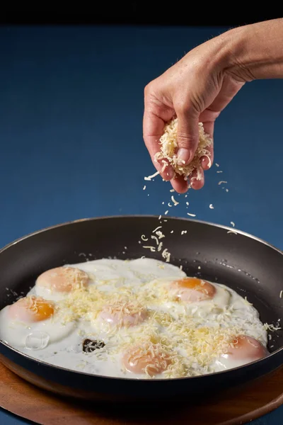 Tavada Kızarmış Yumurta Üzerine Rendelenmiş Çedar Peyniri Serpiştiren Kadın — Stok fotoğraf