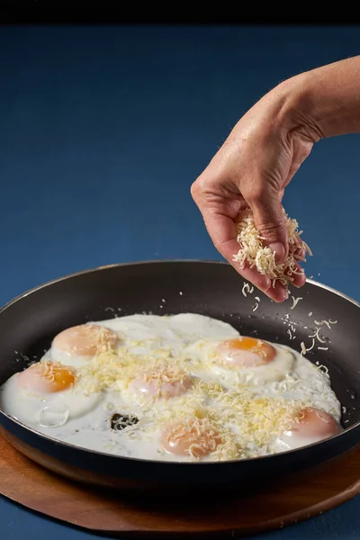 Woman Sprinkling Grated Cheddar Cheese Frying Eggs Pan — Stock Photo, Image