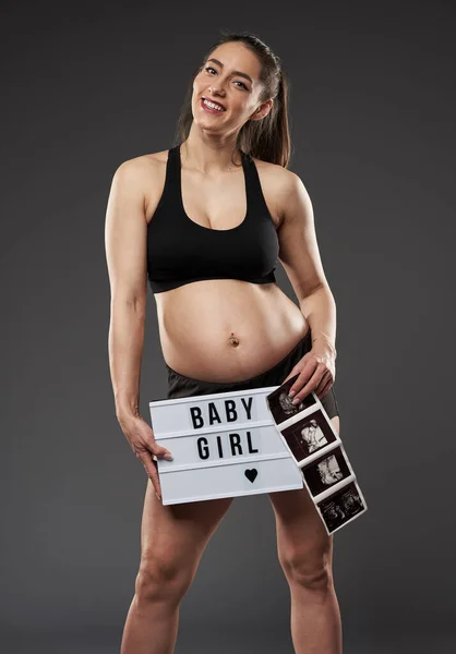若い妊娠中のフィットネス女性誇らしげに彼女の赤ちゃん胎児形態スキャンを示す — ストック写真