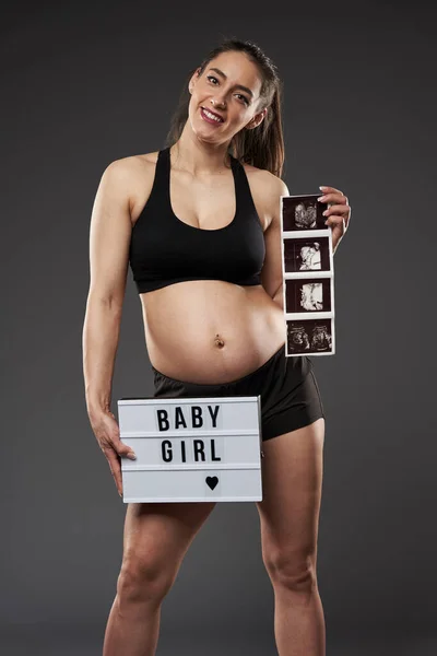 若い妊娠中のフィットネス女性誇らしげに彼女の赤ちゃん胎児形態スキャンを示す — ストック写真