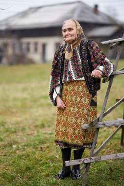 Bahçesinde geleneksel popüler kostümlü yaşlı Romen kadın