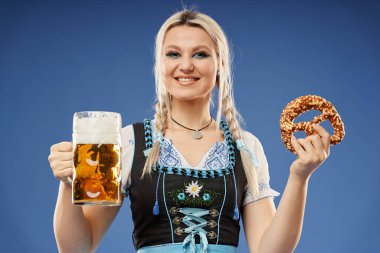 Geleneksel kostümlü, bira bardağıyla sarışın genç bir Alman kadın.
