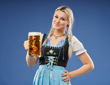 Geleneksel kostümlü, bira bardağıyla sarışın genç bir Alman kadın.
