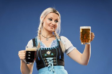 Geleneksel kostümlü, bira bardağıyla sarışın genç bir Alman kadın.