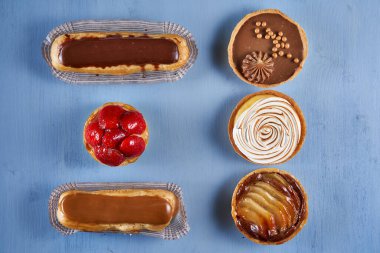 Mavi ahşap zemin üzerinde çeşitli Fransız tatlıları