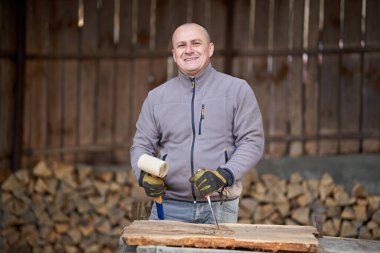 Marangoz ceviz ağacında çekiç ve keskiyle çalışıyor.