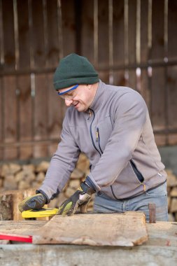 Marangoz kulübedeki ceviz ağacı projesini ölçüp çiziyor.