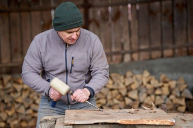Marangoz ceviz ağacında çekiç ve keskiyle çalışıyor.