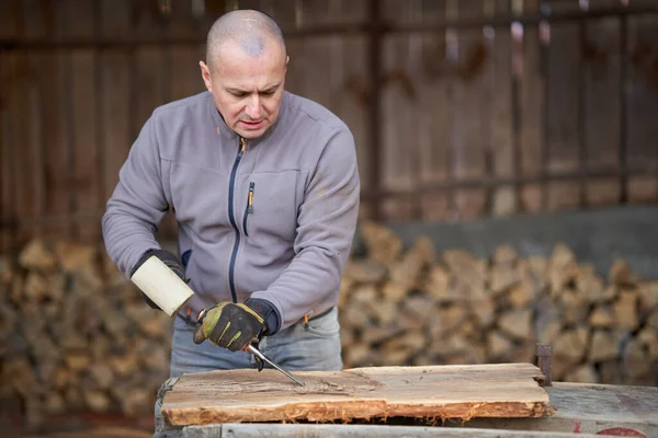 Carpenter working with hammer and chisel on a walnut wood
