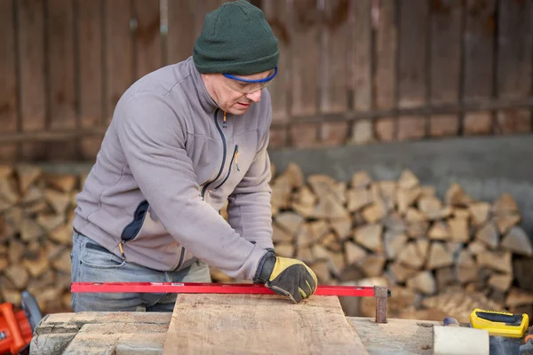 Carpenter measuring and drawing on his walnut wood project in the shed