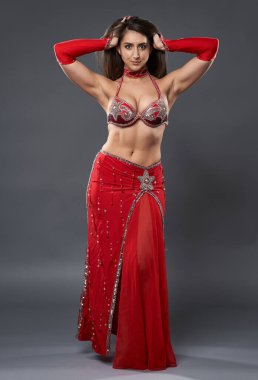 Arap kadın dansçı, gri arka planda kırmızı, ışıltılı kostümlü.