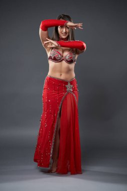 Arap kadın dansçı, gri arka planda kırmızı, ışıltılı kostümlü.