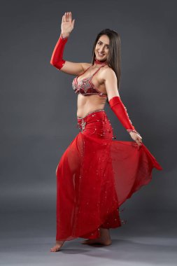 Arap kadın dansçı, gri arka planda kırmızı, ışıltılı kostümlü.