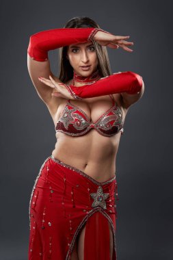 Arap kadın dansçı, gri arka planda kırmızı, ışıltılı kostümlü.