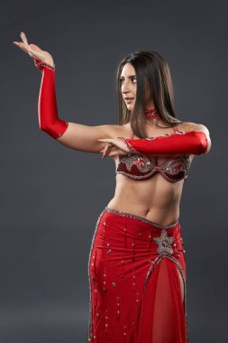 Arap kadın dansçı, gri arka planda kırmızı, ışıltılı kostümlü.