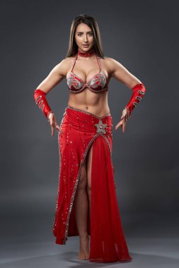 Arap kadın dansçı, gri arka planda kırmızı, ışıltılı kostümlü.