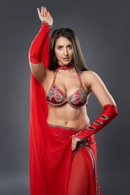 Arap kadın dansçı, gri arka planda kırmızı, ışıltılı kostümlü.