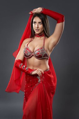 Arap kadın dansçı, gri arka planda kırmızı, ışıltılı kostümlü.