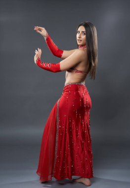 Arap kadın dansçı, gri arka planda kırmızı, ışıltılı kostümlü.