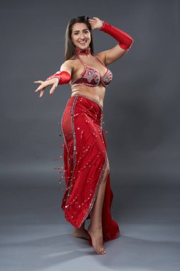 Arap kadın dansçı, gri arka planda kırmızı, ışıltılı kostümlü.