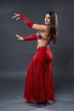 Arap kadın dansçı, gri arka planda kırmızı, ışıltılı kostümlü.