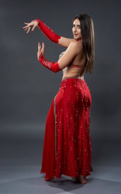 Arap kadın dansçı, gri arka planda kırmızı, ışıltılı kostümlü.