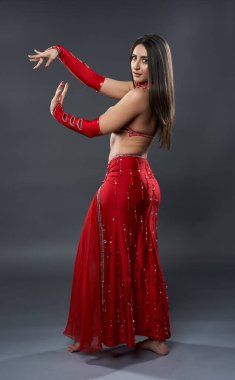 Arap kadın dansçı, gri arka planda kırmızı, ışıltılı kostümlü.