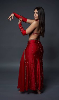 Arap kadın dansçı, gri arka planda kırmızı, ışıltılı kostümlü.