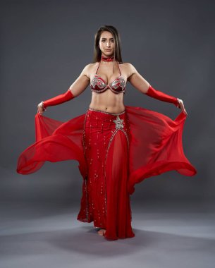 Arap kadın dansçı, gri arka planda kırmızı, ışıltılı kostümlü.