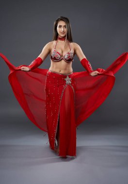 Arap kadın dansçı, gri arka planda kırmızı, ışıltılı kostümlü.