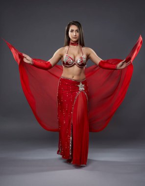 Arap kadın dansçı, gri arka planda kırmızı, ışıltılı kostümlü.