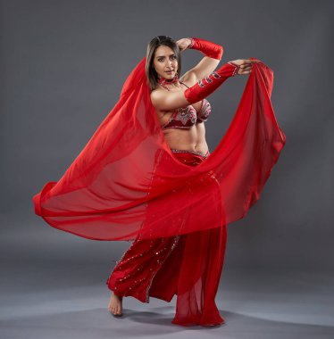 Arap kadın dansçı, gri arka planda kırmızı, ışıltılı kostümlü.