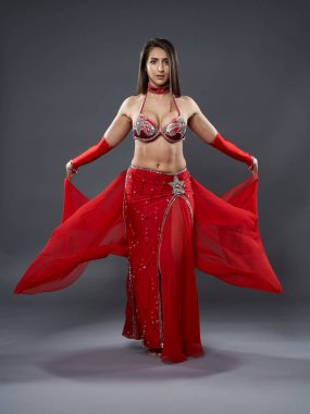 Arap kadın dansçı, gri arka planda kırmızı, ışıltılı kostümlü.