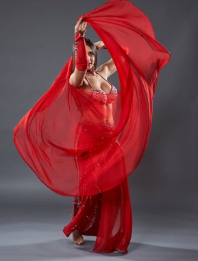 Arap kadın dansçı, gri arka planda kırmızı, ışıltılı kostümlü.