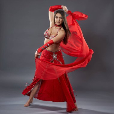 Arap kadın dansçı, gri arka planda kırmızı, ışıltılı kostümlü.