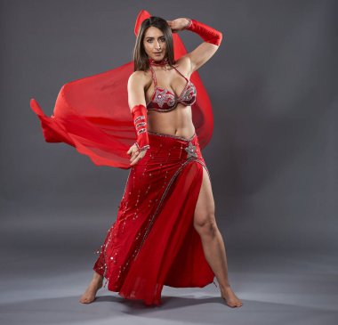 Arap kadın dansçı, gri arka planda kırmızı, ışıltılı kostümlü.